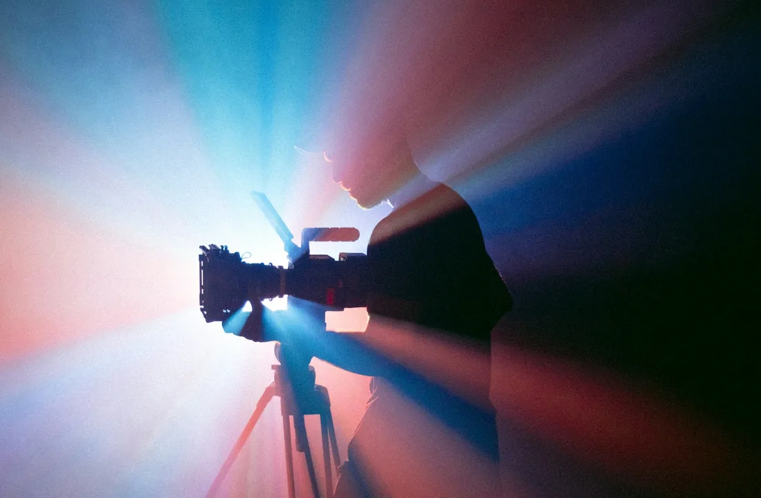 Caméra de tournage installée sur un trépied dans un éclairage de studio coloré